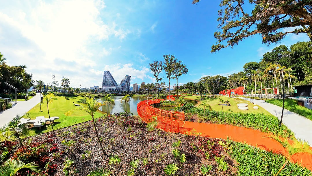 Parque Viva Energia com o lago, a passarela laranja e o Vértice ao fundo, setembro de 2026